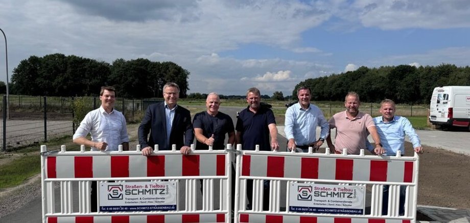 Ein Bild mit 7 Personen auf einer Straße mit einer Absperrung